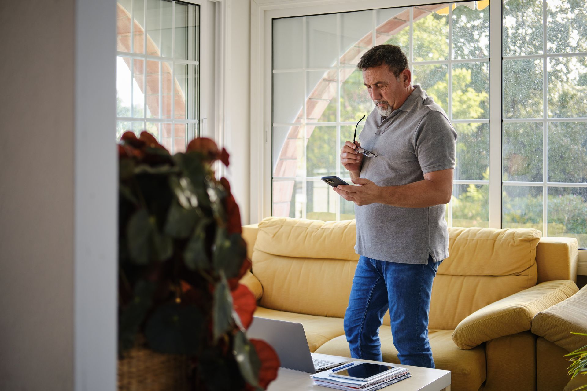 Man checking a high summer electric bill on his phone inside a bright Springfield, MO home.