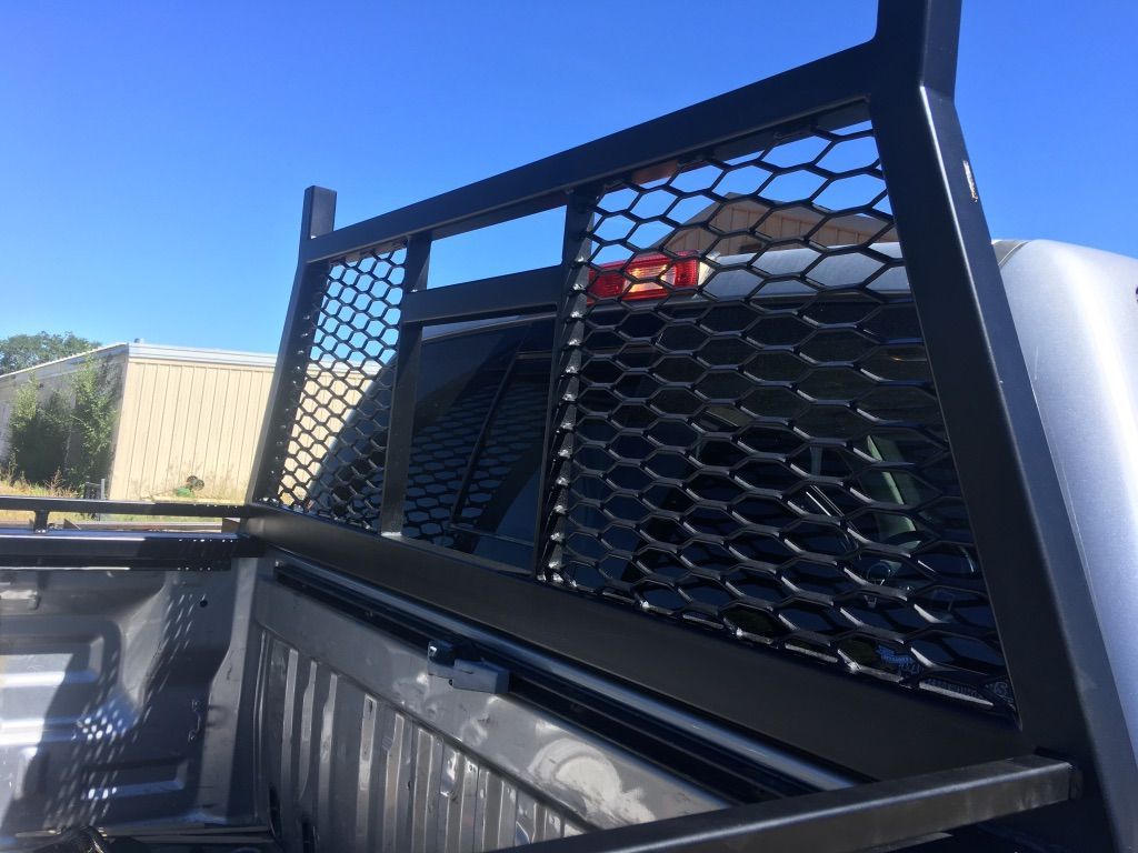 The back of a truck with a mesh headache rack on it.