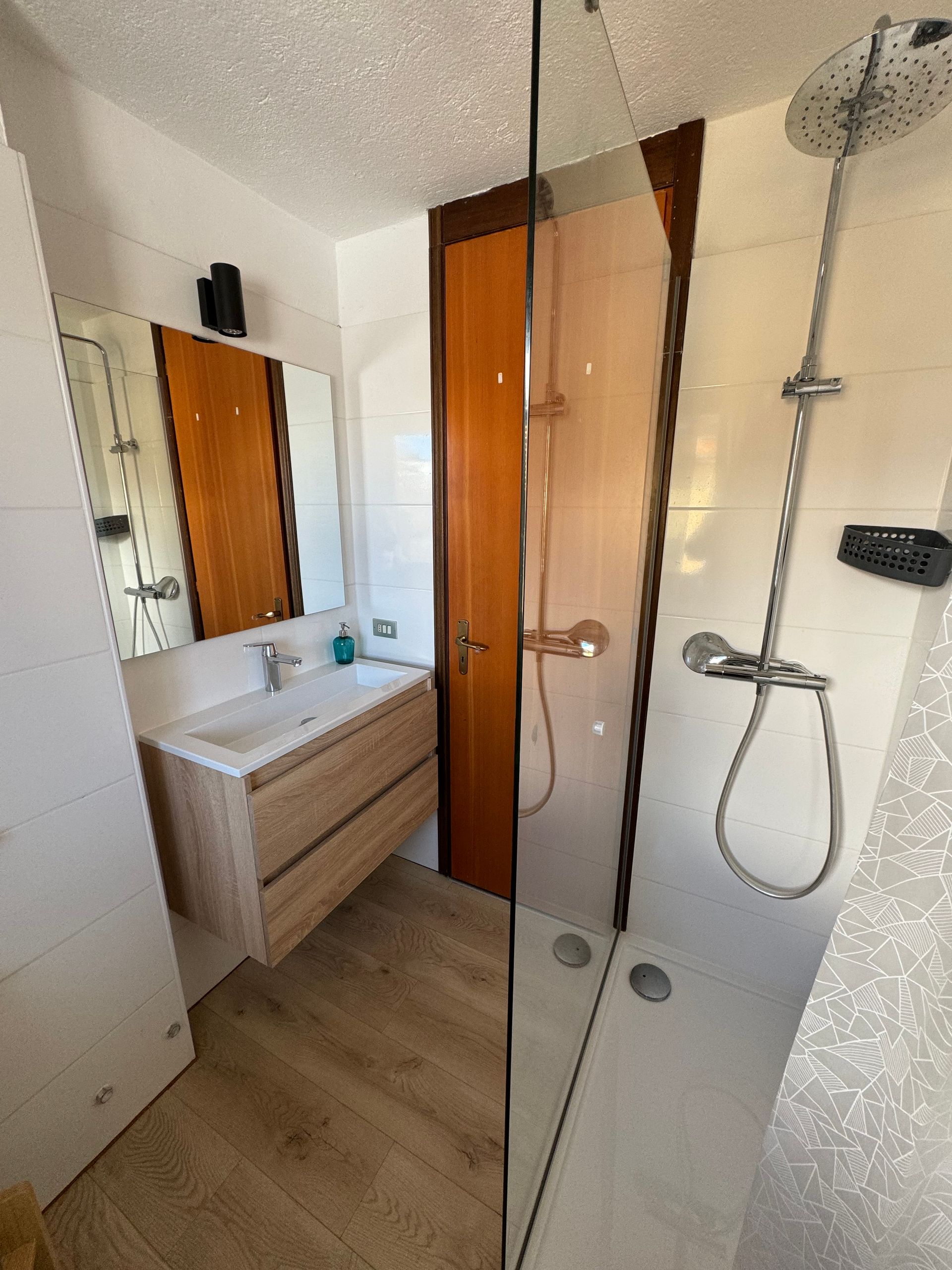 Bathroom seeing the shower and the sink with a mirror.