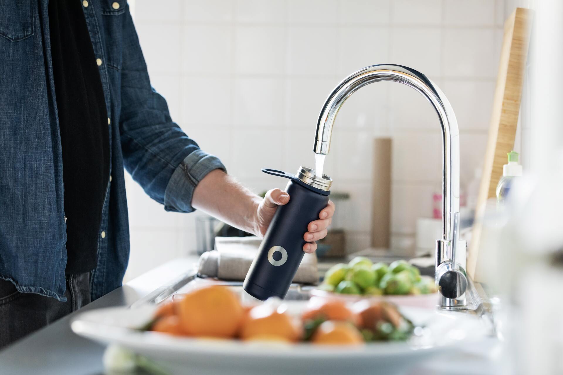 Persona llenado un termo con agua para beber del grifo Persona llenado un termo con agua para beber del grifo