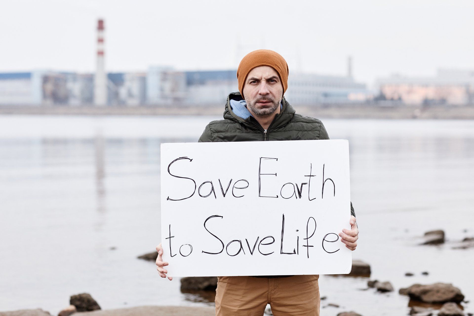Retrato de hombre sosteniendo el signo de salvar la tierra y mirando a la cámara mientras protestaba por la discapacidad ambiental Retrato de hombre sosteniendo el signo de salvar la tierra y mirando a la cámara mientras protestaba por la discapacidad ambiental