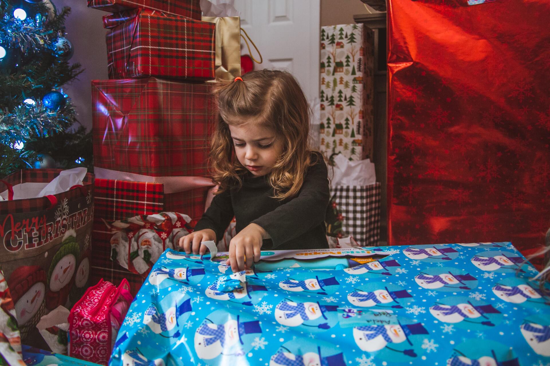niña abriendo con cuidado su regalos para limitar la generación de basura niña abriendo con cuidado su regalos para limitar la generación de basura
