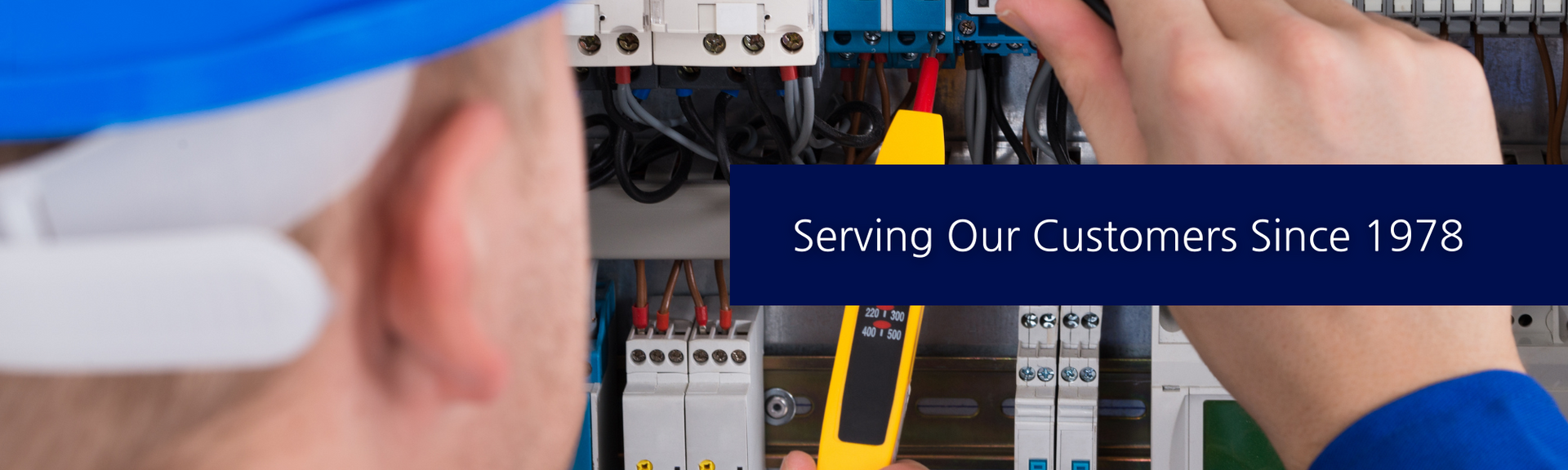 A technician in a hard hat uses a yellow electrical tester on a circuit breaker panel. Text reads: