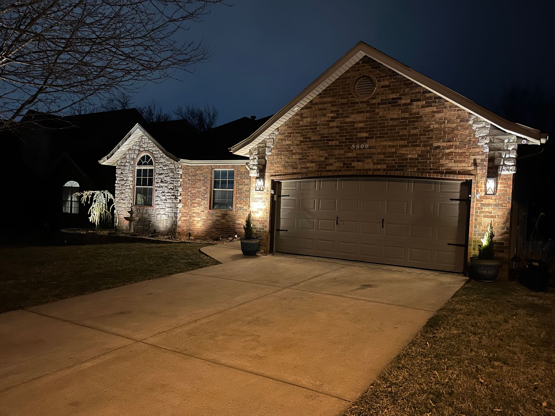 A brick house with a garage is lit up at night