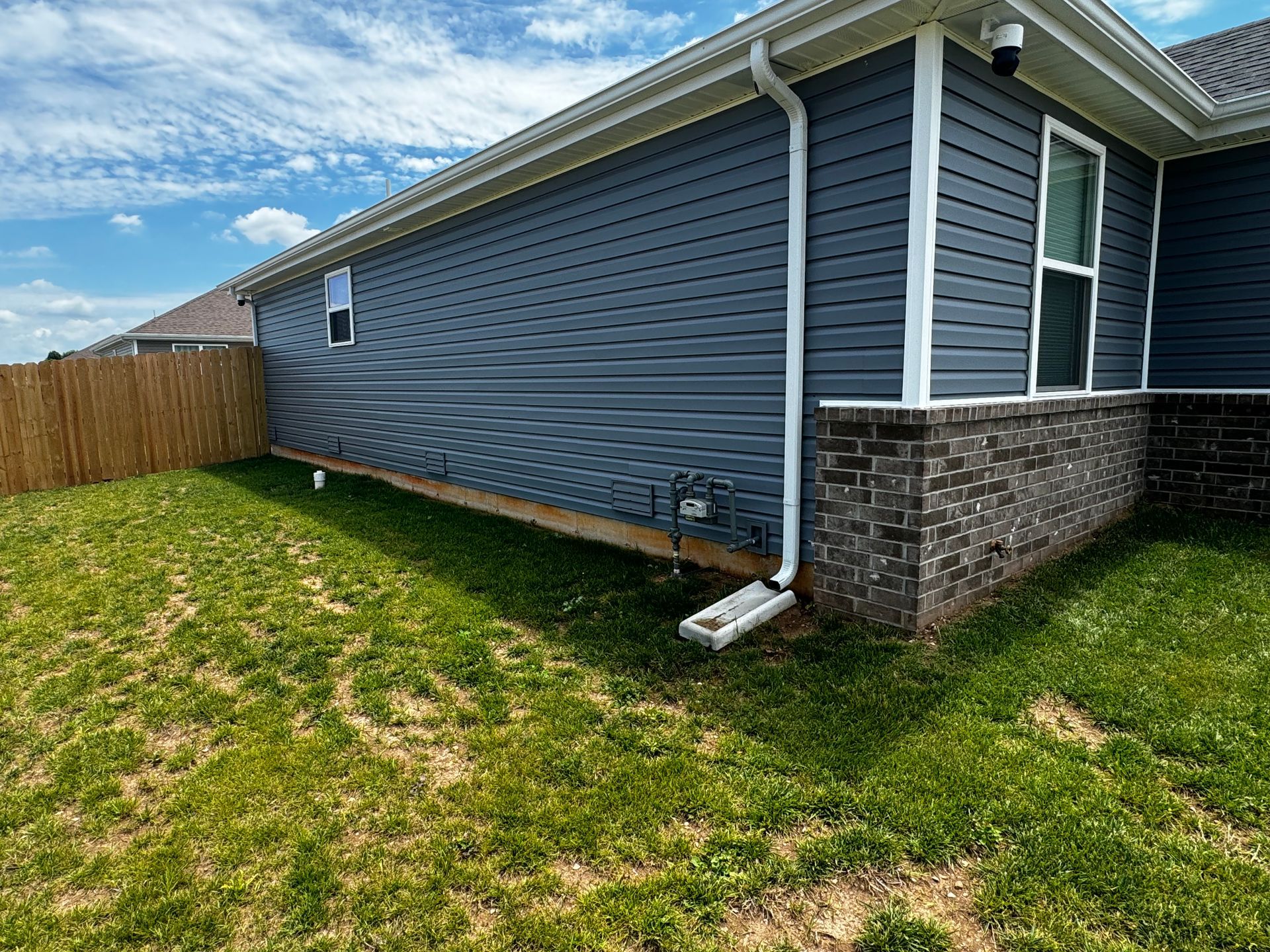 The backyard of a house with a blue siding and a white gutter