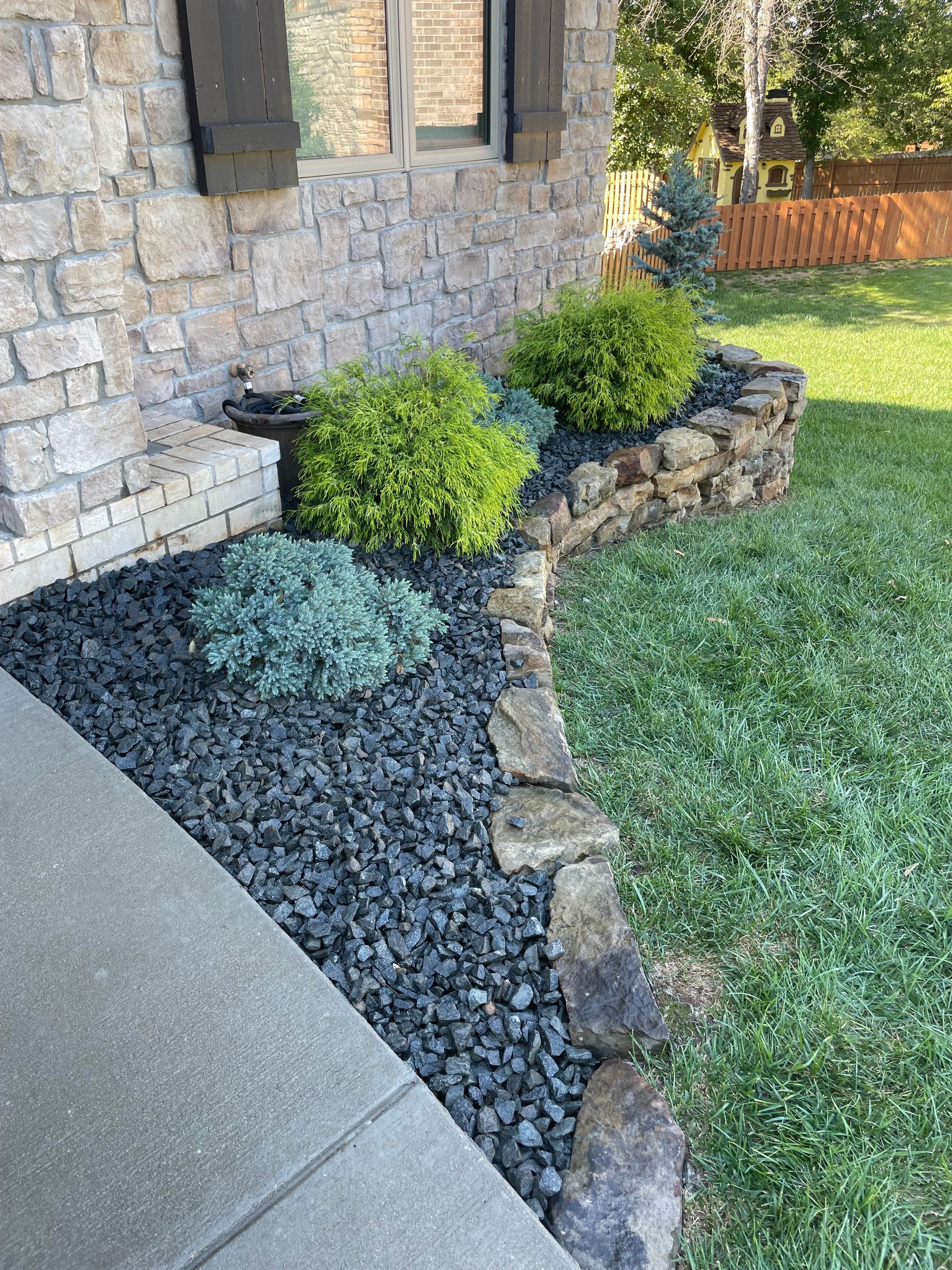 A brick house with a lush green lawn and a stone wall.