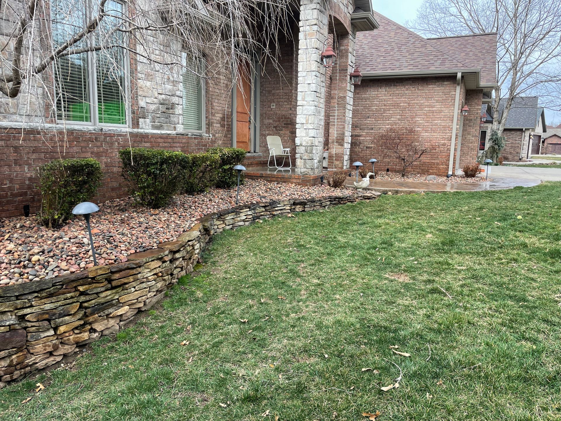 A brick house with a lush green lawn in front of it