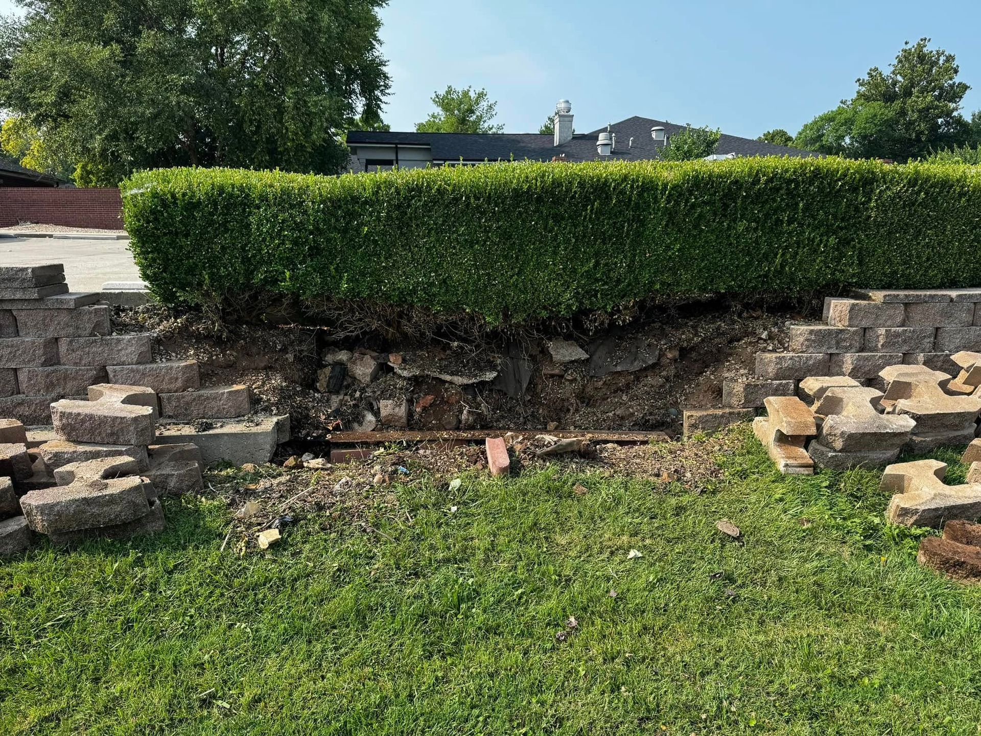 A brick wall is sitting in the middle of a lush green field.