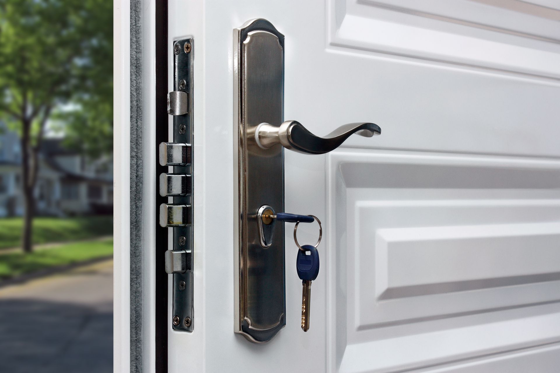 White door with silver lockset and keys, opening to a suburban street scene — North East Locksmiths in Wodonga, VIC