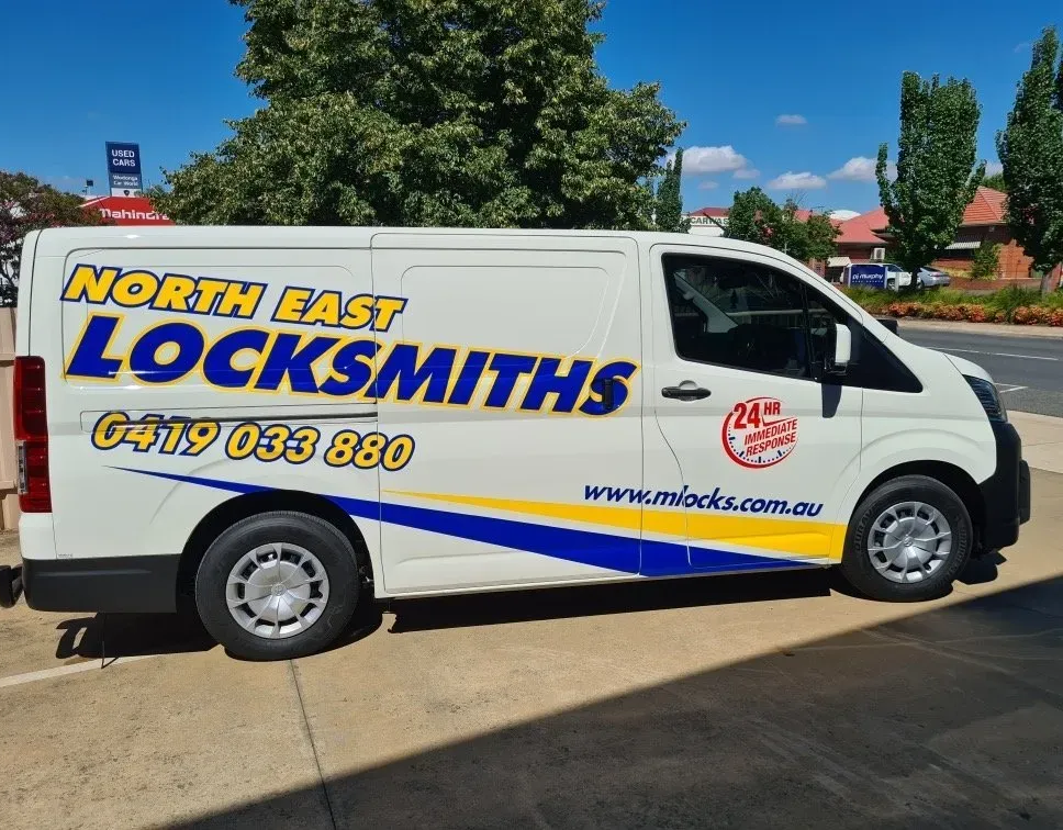 White Van With A North East Locksmiths Logo and Contact Info Parked on a Sunny Street — North East Locksmiths in Wodonga, VIC