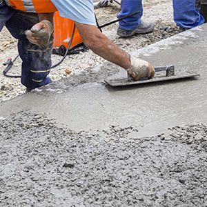 Worker smoothing fresh concrete with a trowel at a construction site