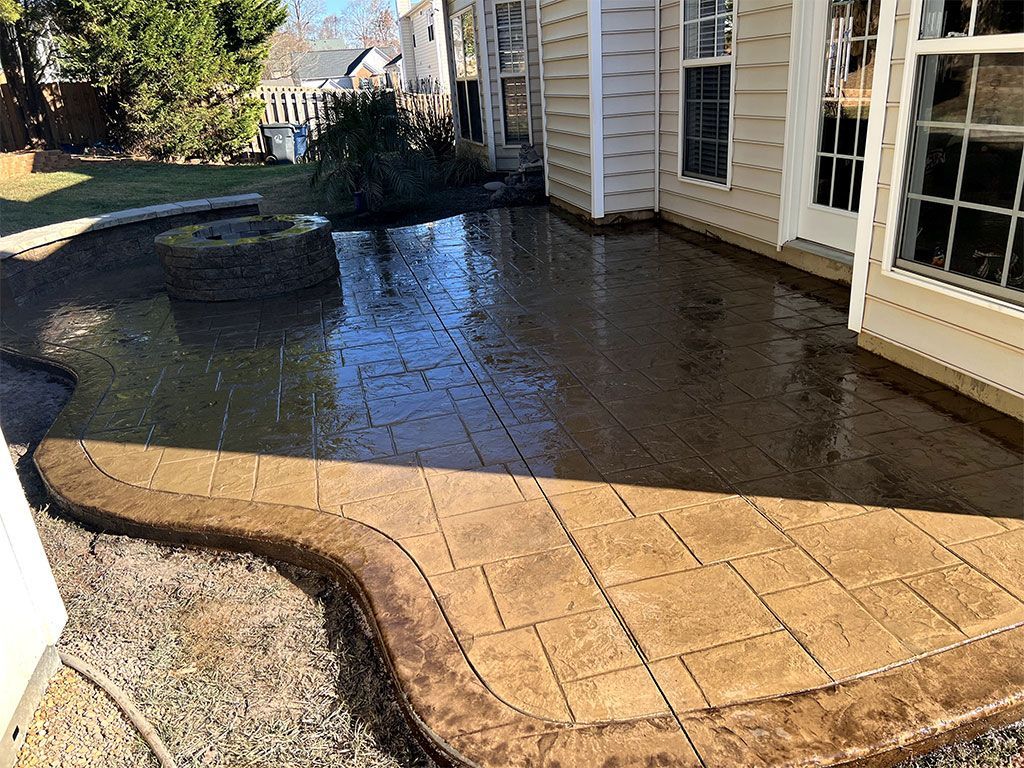Flooded backyard patio beside a beige house, with pooled water over concrete and gravel.