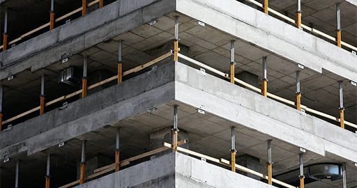 Multi-story concrete building under construction with exposed beams and support columns