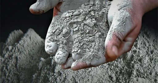 Hands holding gray cement powder close-up