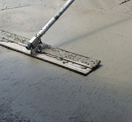 Concrete floor being smoothed with a long-handled trowel