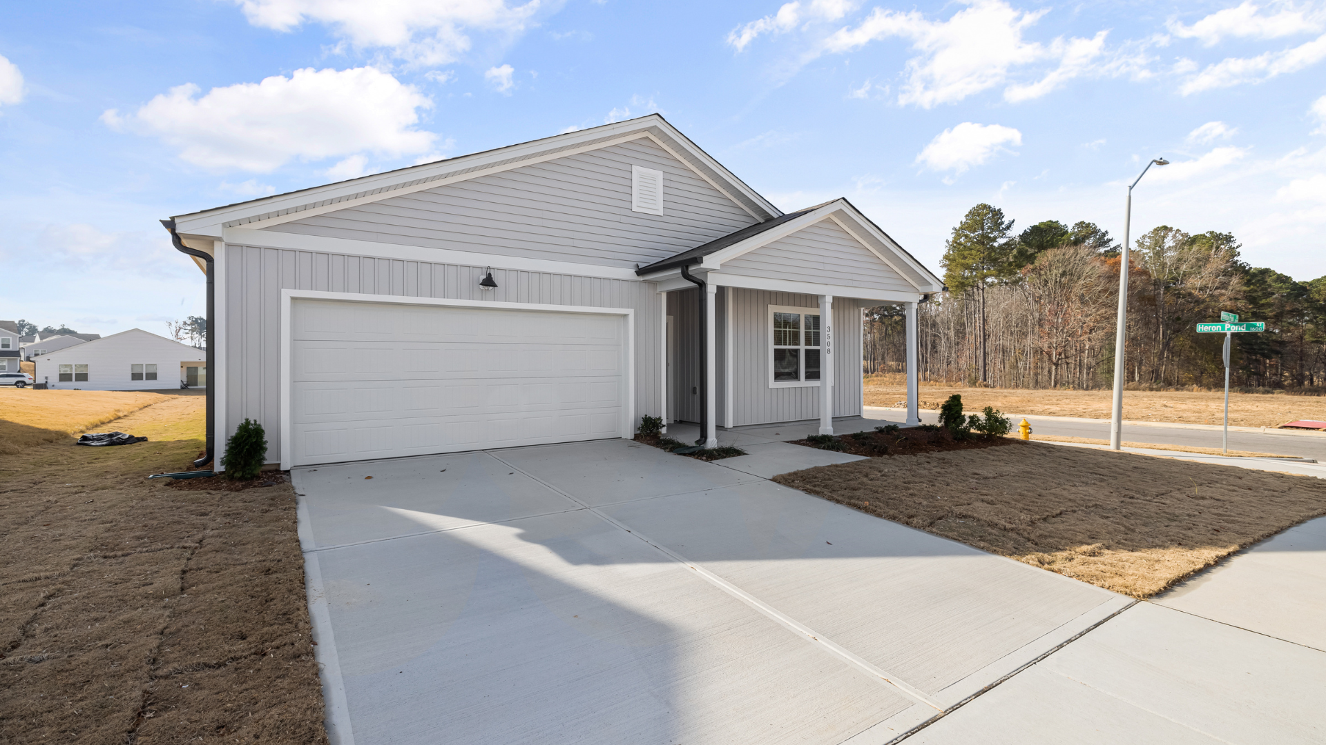 New single-story house with two-car garage and concrete driveway in a bare lot