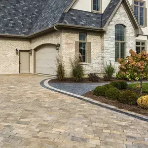 Stone house with arched garage, paved driveway, and landscaped front yard