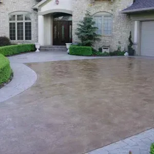 Suburban stone house with a wet concrete driveway, garage, and trimmed hedges