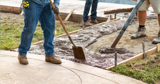 Workers shoveling wet concrete at a sidewalk repair site