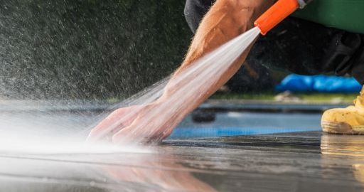 Orange brush sweeping water across a wet floor for cleaning