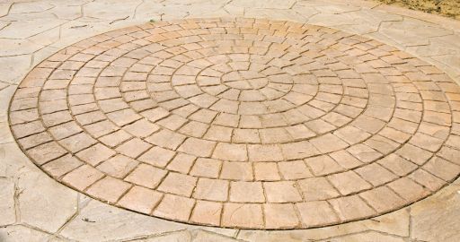 Circular stone mosaic pavement on a light tan surface