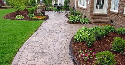 Curved stone walkway through a landscaped garden beside a brick house