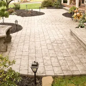 Stone patio walkway with decorative lanterns, bordered by garden beds and stone benches