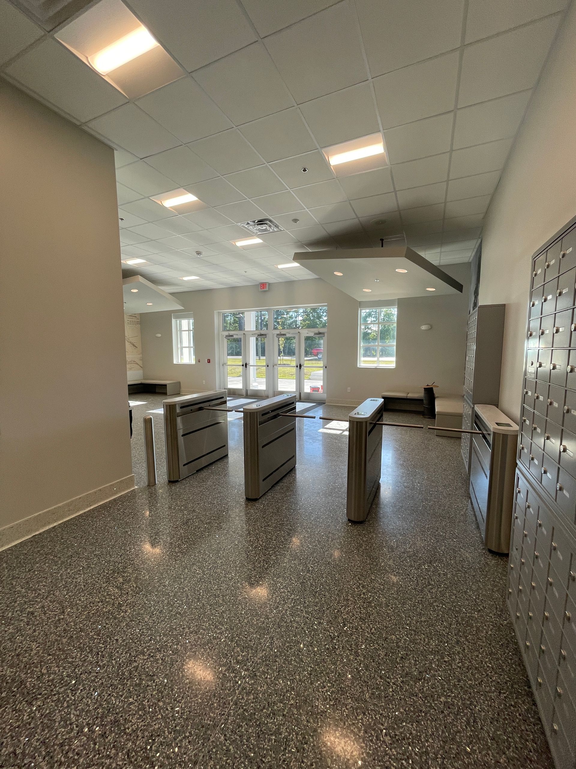 Hallway with terrazzo floor, security turnstiles, and doors to outside.