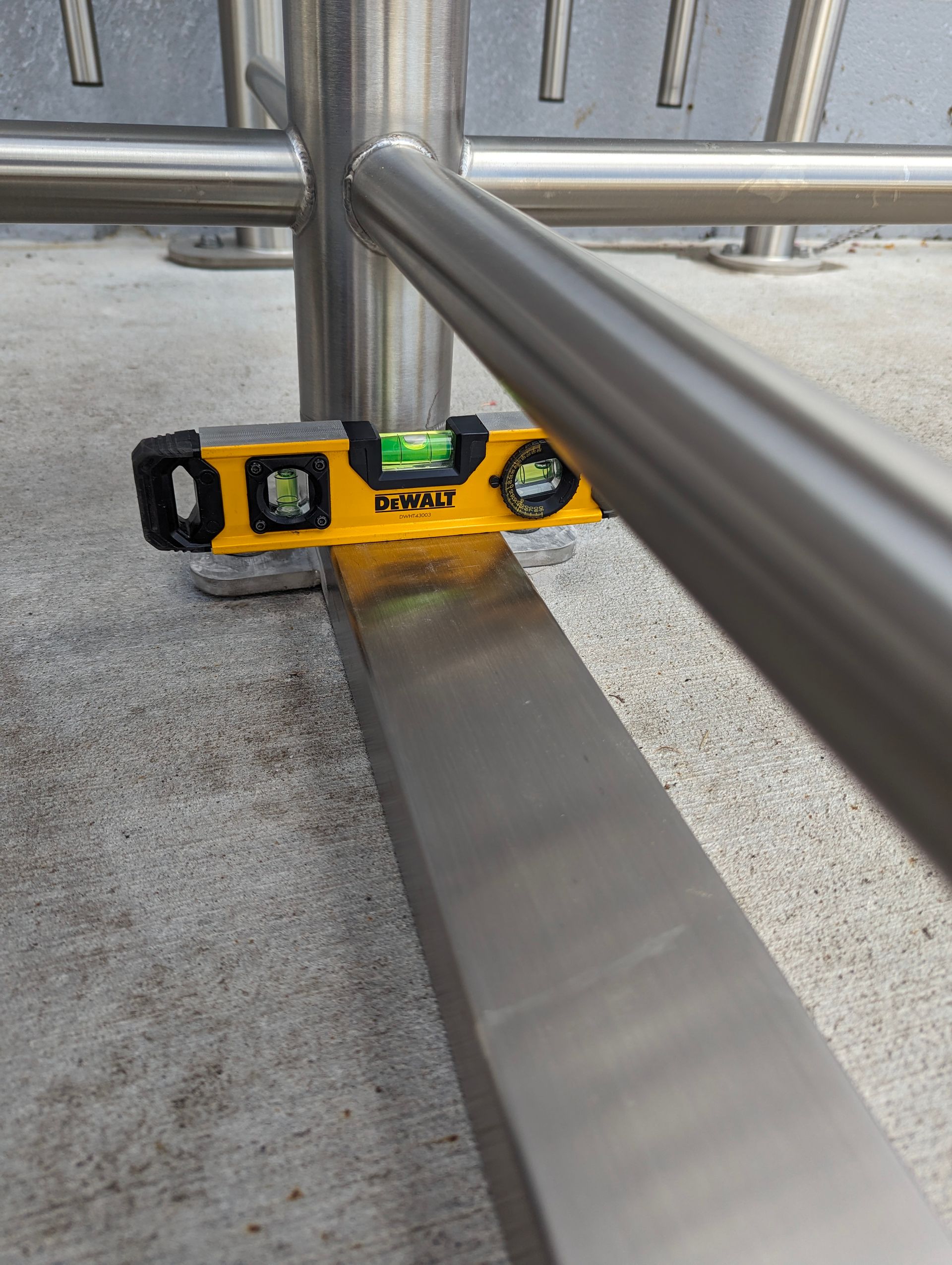 Yellow level on a metal beam, testing the level of a metal rail outdoors.