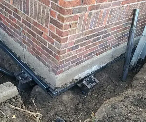 A brick wall with a hole in the ground in front of it. A brick wall with a hole in the ground in front of it.