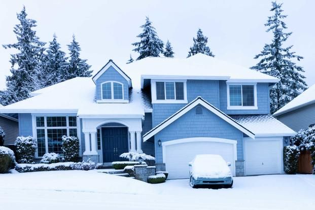 A blue house with a car parked in front of it covered in snow A blue house with a car parked in front of it covered in snow
