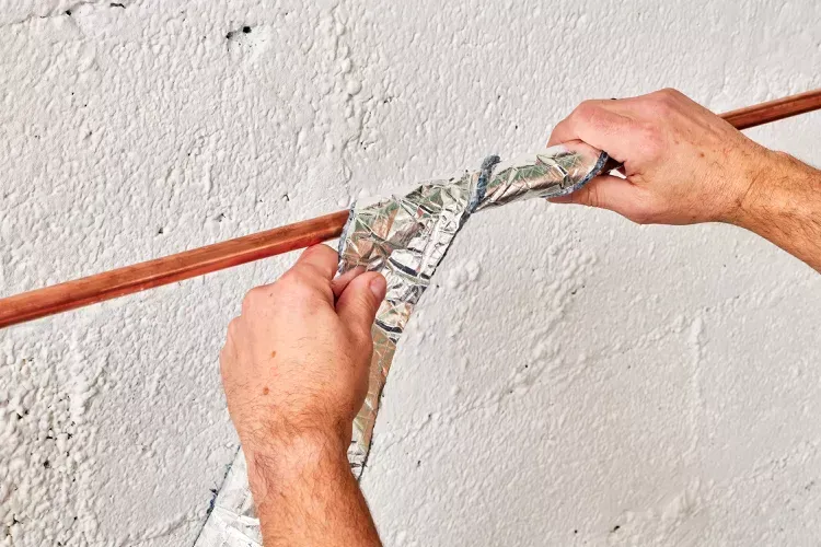 A person is wrapping a pipe with aluminum foil. A person is wrapping a pipe with aluminum foil.