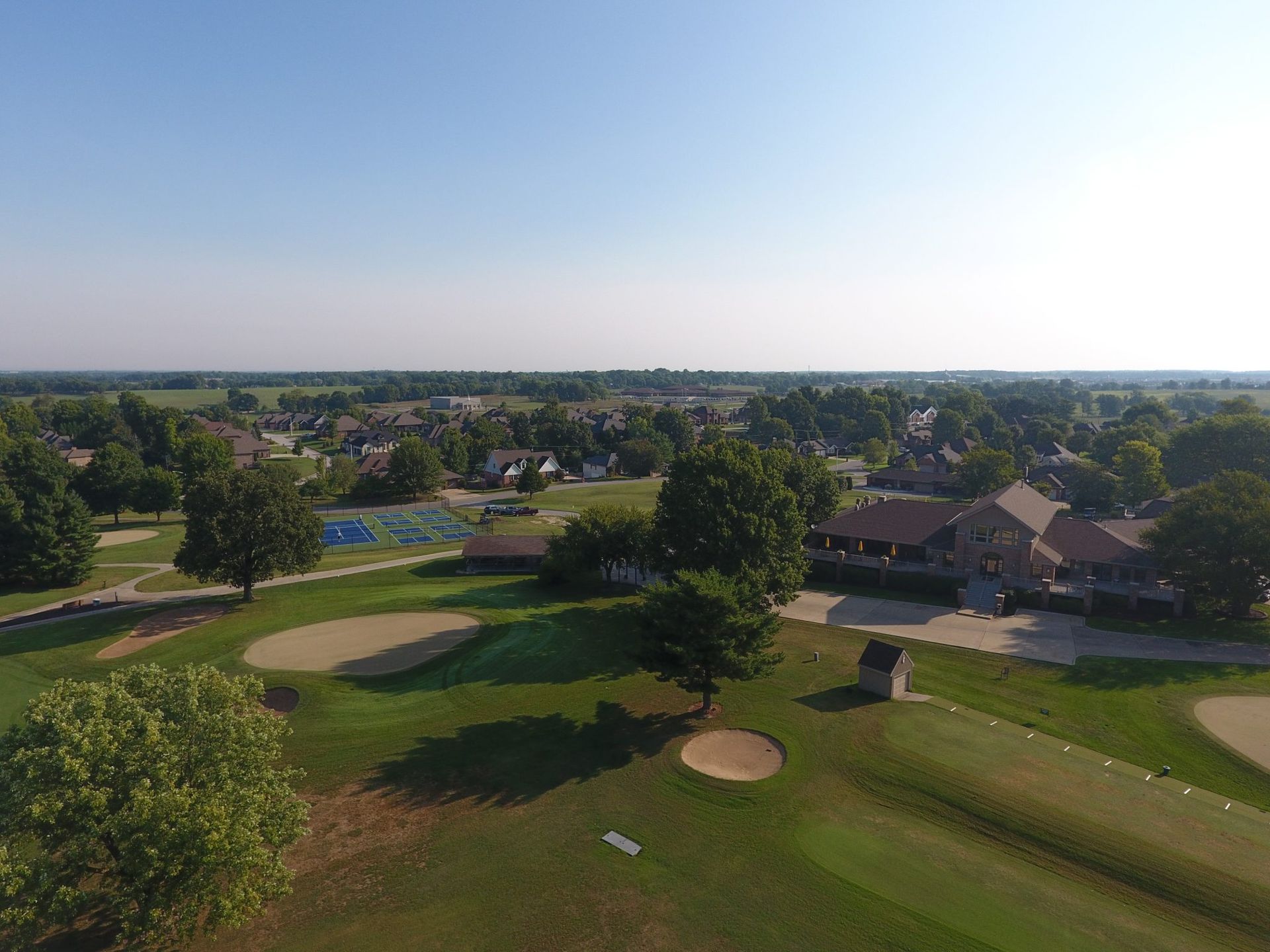 An aerial view of a golf course with houses in the background.