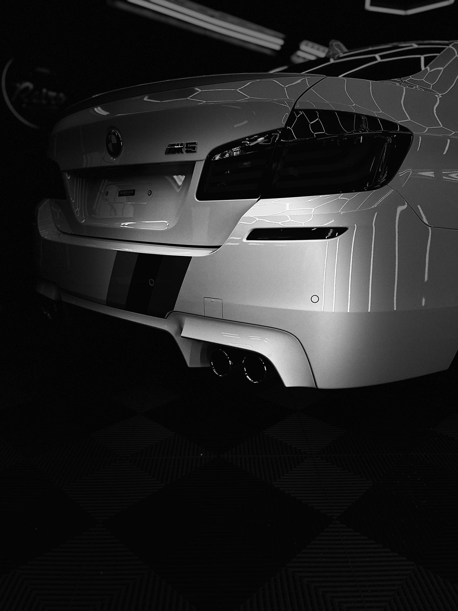 White sports car front end in a dark studio, with glossy black headlights and bumper details.