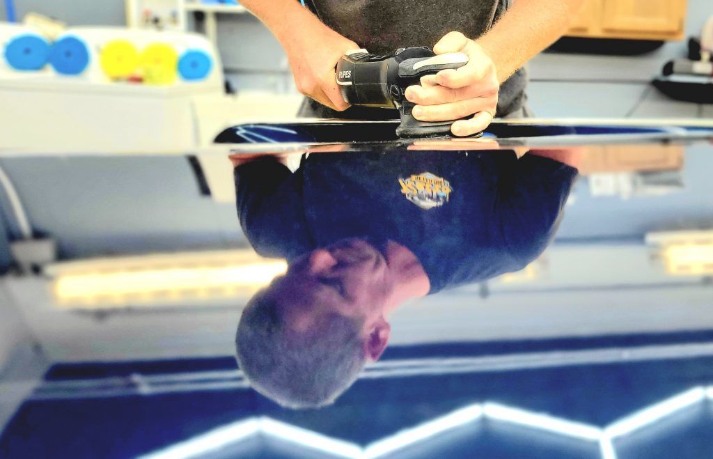 Person holding a camera over a reflective glass surface in a bright indoor setting