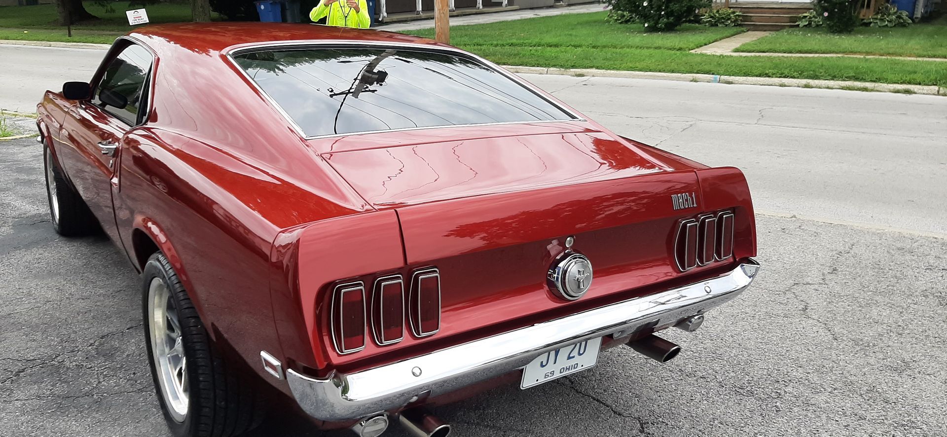 Red classic Ford Mustang parked on a suburban street, rear view.