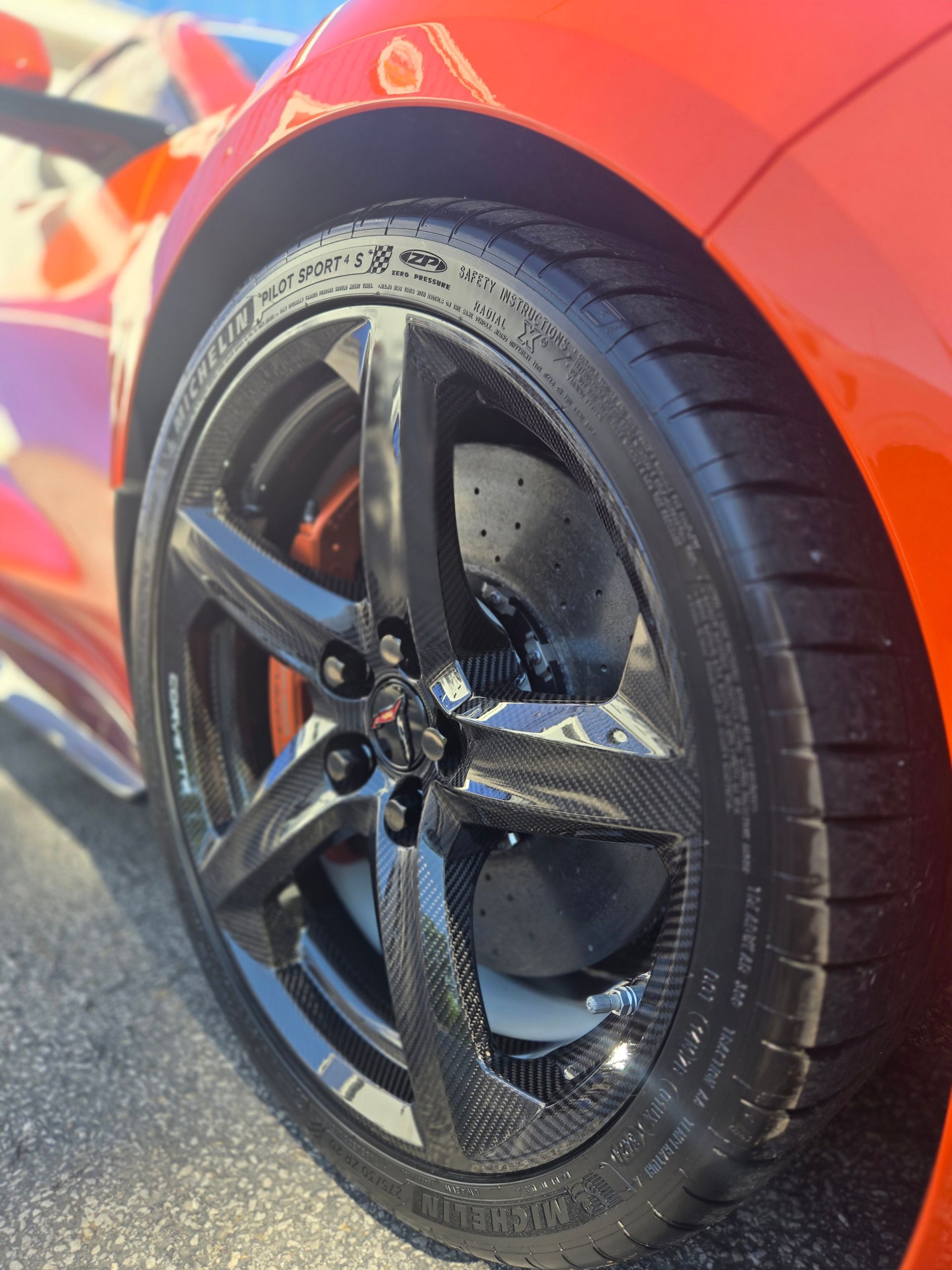 Close-up of a black alloy wheel and tire on a red sports car.