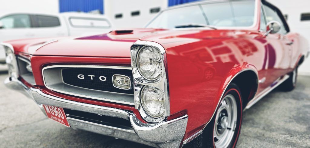 Red classic Pontiac GTO convertible parked indoors, front angled view.