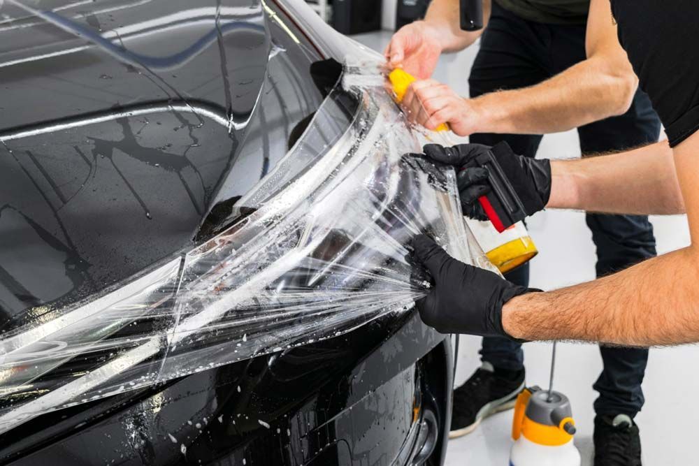 Close-up of a glossy black car body with reflective light streaks