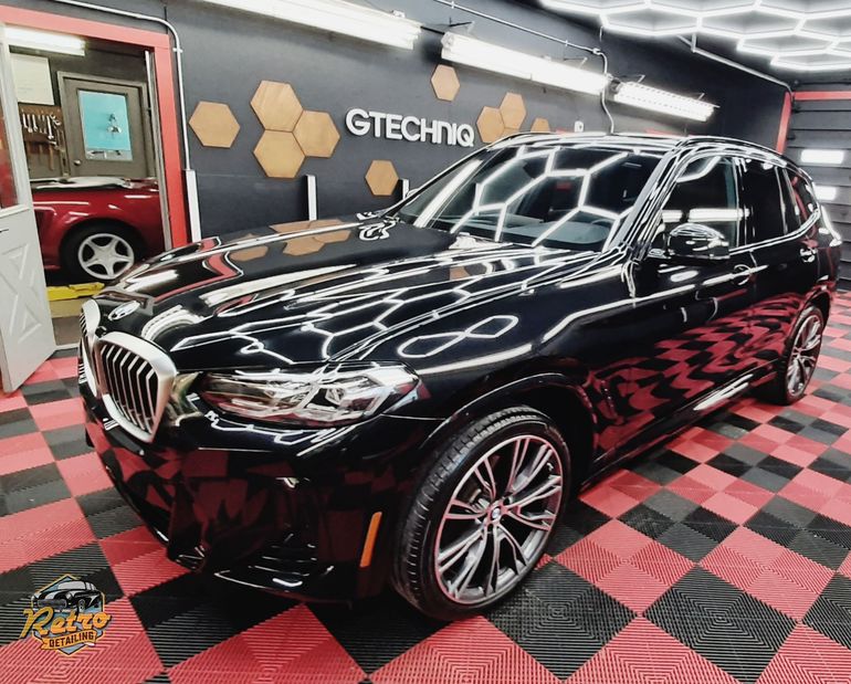 Close-up of a red car key fob on a black honeycomb-patterned car hood