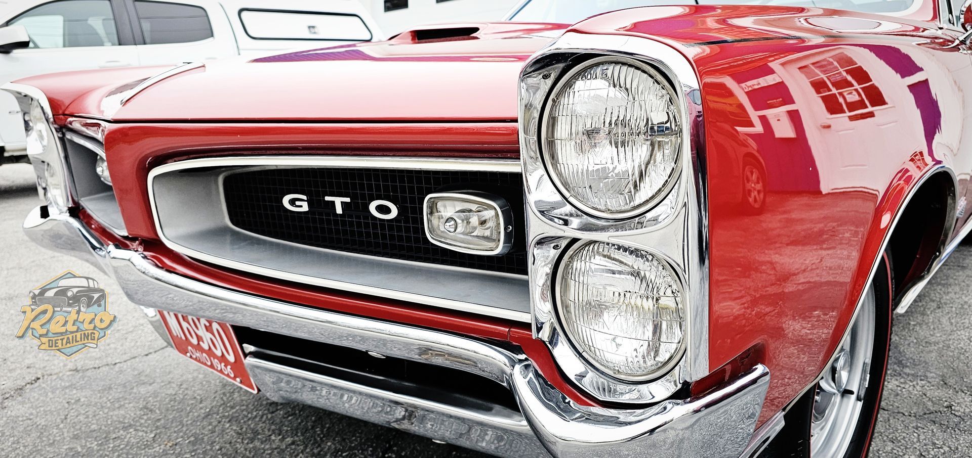 Close-up of a red Pontiac GTO front grille and headlights in a car show setting