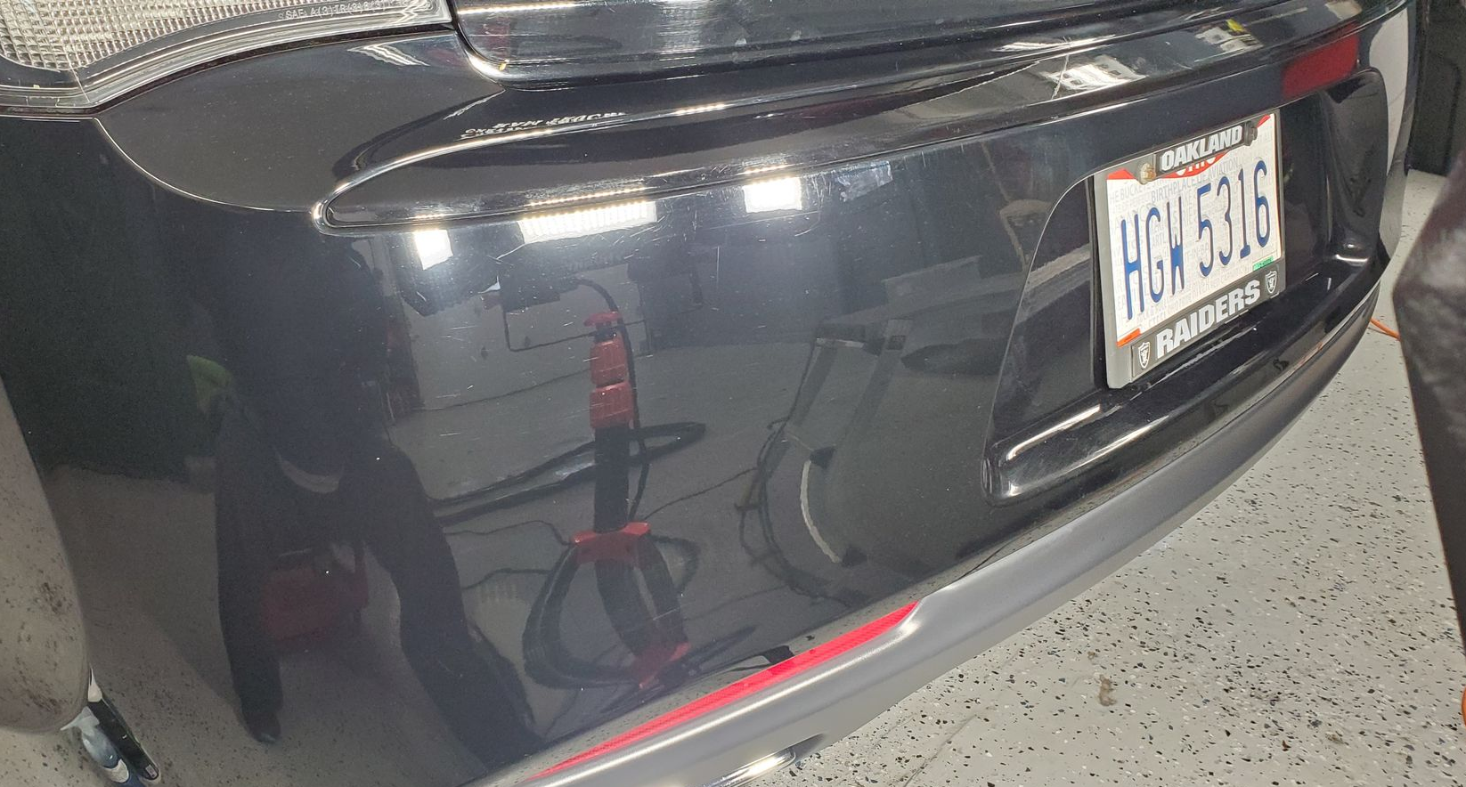 Rear view of a dark sedan with a license plate in a parking lot