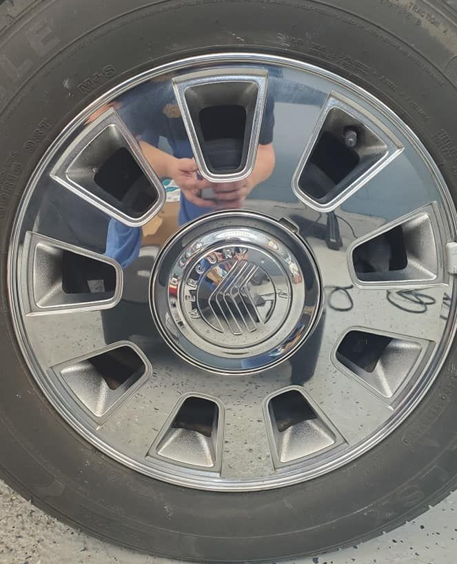 Close-up of a chrome truck wheel with reflective hubcap and black tire.