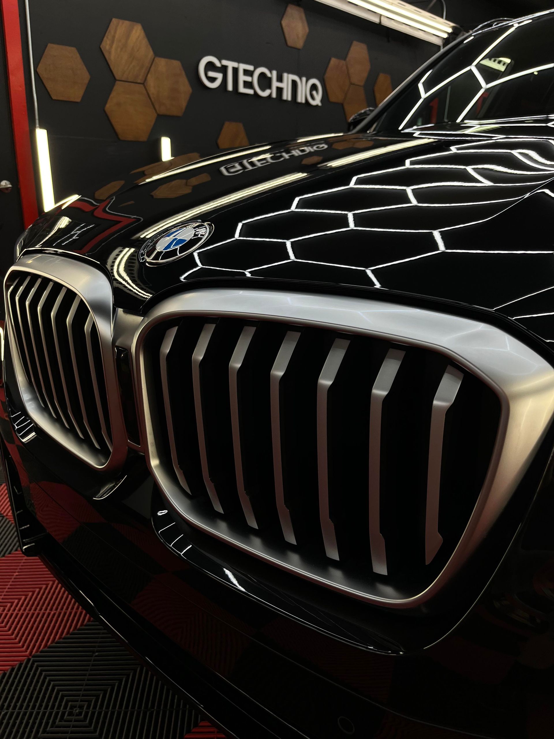 Close-up of a black BMW grille with chrome accents at a GTECHNIQ display
