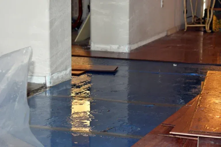 A room interior undergoing flooring installation, featuring blue underlayment and partially laid wood planks.