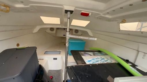 Interior of a white van with folded seats, a central support pole, and cargo items on the floor