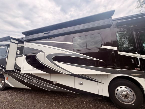 Person cleaning the windows of a white RV parked by the coast