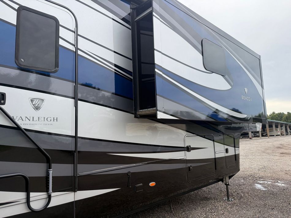 Person washing a white RV with a hose outdoors