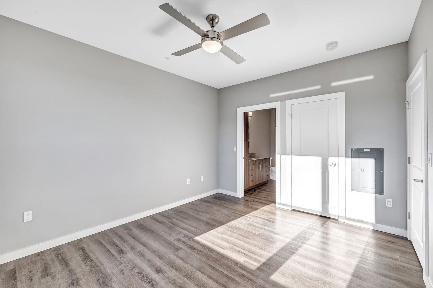 An empty room with a ceiling fan and hardwood floors.