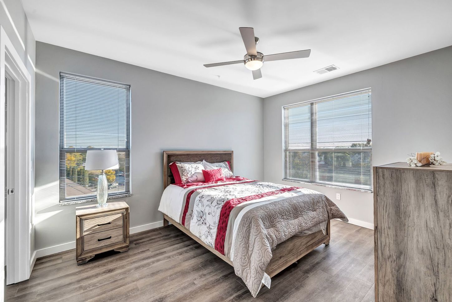 A bedroom with a bed , nightstand , dresser and ceiling fan.